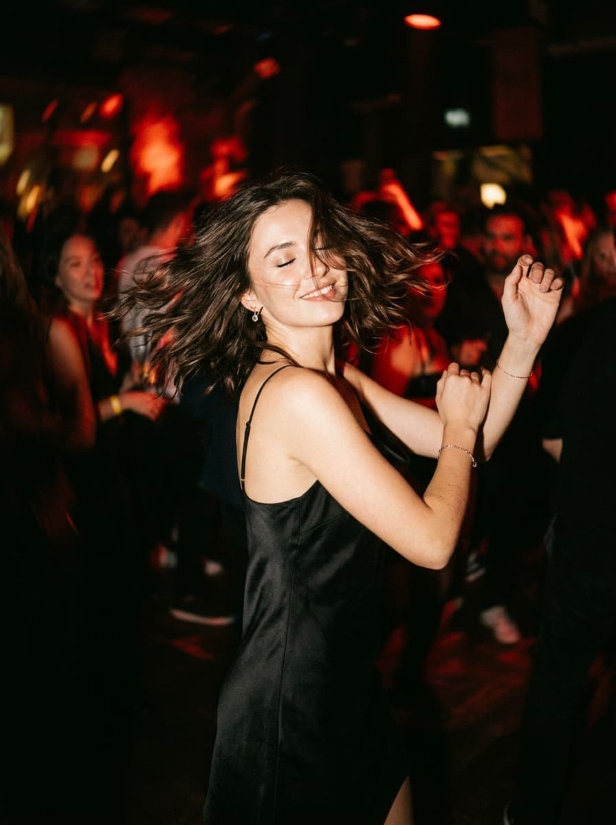 Mujer bailando con vestido negro bajo luz roja